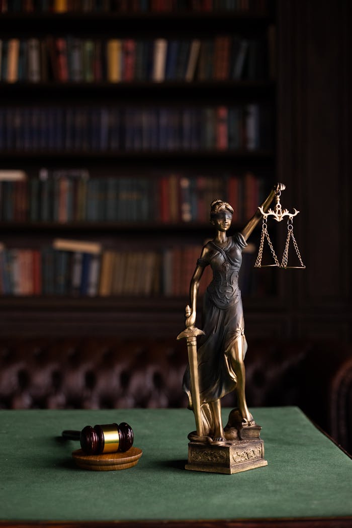 about-us-01 Lady Justice and gavel on a table in a classic law library setting.